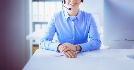 Serious pretty young woman working as support phone operator with headset in officeの写真素材