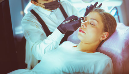 Cosmetologist applying permanent make up on eyebrowsの写真素材