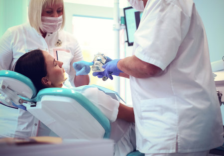 Senior male dentist in dental office talking with female patient and preparing for treatmentの写真素材