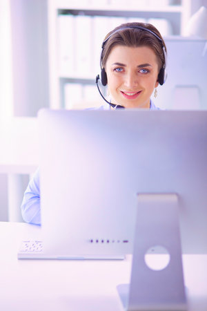 Serious pretty young woman working as support phone operator with headset in officeの写真素材