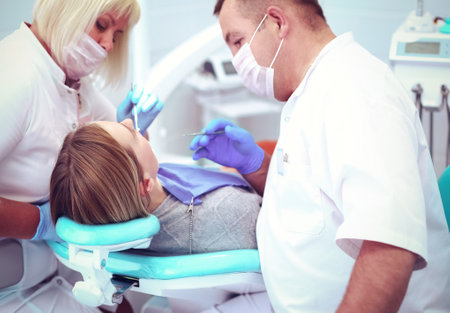 Dentist and his assistant carrying out a thorough examinationの写真素材