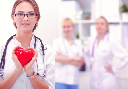 Female doctor with stethoscope holding heart in her arms. Healthcare and cardiology concept in medicineの写真素材