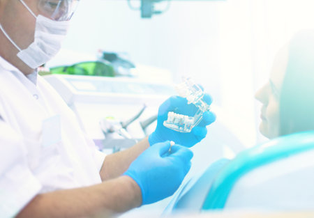 Senior male dentist in dental office talking with female patient and preparing for treatmentの写真素材