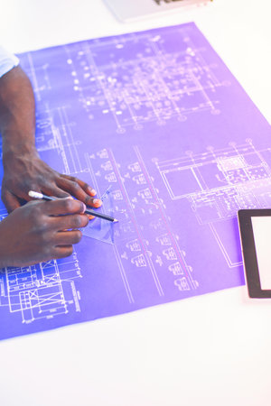 African american architect working with computer and blueprints in officeの写真素材