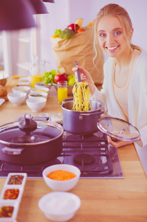 Beautiful young woman cooking in kitchen at homeの写真素材