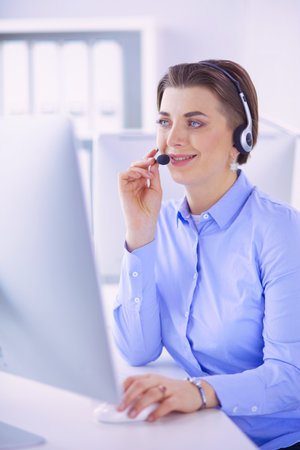 Serious pretty young woman working as support phone operator with headset in officeの写真素材