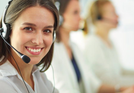 Smiling businesswoman or helpline operator with headset and computer at officeの写真素材