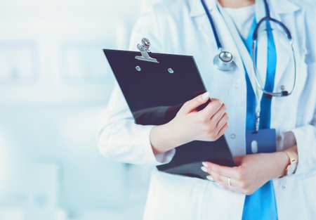 Smiling female doctor with a folder in uniform standingの写真素材