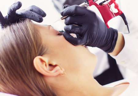 Microblading eyebrows work flow in a beauty salon. Woman having her eye brows tintedの写真素材