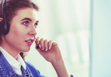 Portrait of beautiful business woman working at her desk with headset and laptopの写真素材