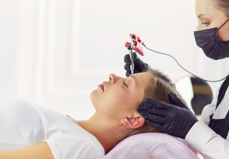 Young woman undergoing procedure of eyebrow permanent makeup in beauty salonの写真素材