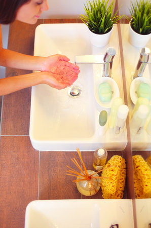 Young woman washing her face with clean water in bathroomの写真素材