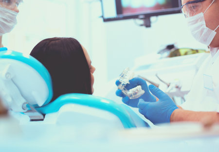 Male dentists examining and working on young female patientの写真素材