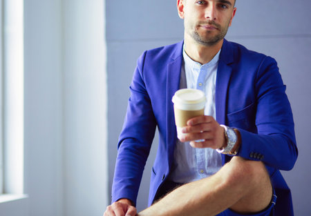 Young businessman sitting isolated on grey background.の写真素材