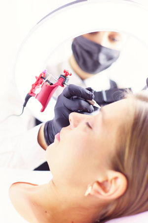 Microblading eyebrows work flow in a beauty salon. Woman having her eye brows tintedの写真素材
