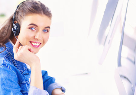 Portrait of beautiful business woman working at her desk with headset and laptopの写真素材