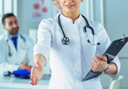 Portrait of young beautiful woman doctor giving handshakeの写真素材