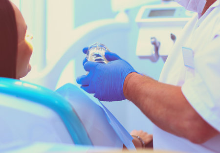 Image of young lady with dentist over her before checking oral cavityの写真素材