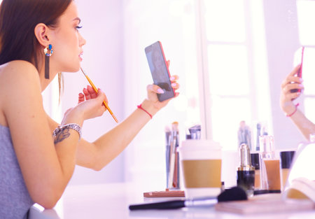 female young beautiful girl with curly hair and make-up. beautiful woman make self-portrait yourself by phoneの写真素材