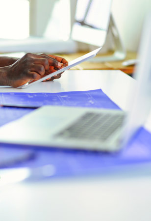 African american architect working with computer and blueprints in officeの写真素材