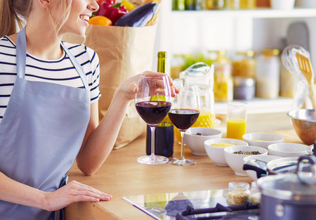 Pretty woman drinking some wine at home in kitchenの写真素材