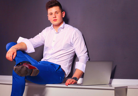 Handsome young man with laptop on black backgroundの写真素材