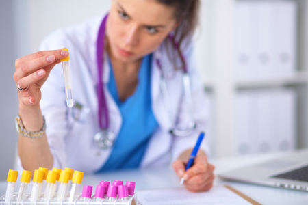 Woman researcher is surrounded by medical vials and flasks, isolated on whiteの写真素材