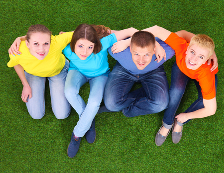Group of young people lying on green grassの写真素材