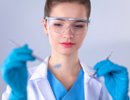 Attractive female dentist with tools , standing on gayの写真素材