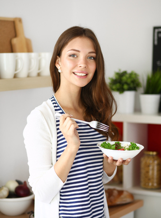 Young woman eating salad and holding a mixed salad .の写真素材
