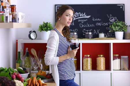 Pretty woman drinking some wine at home in kitchenの写真素材
