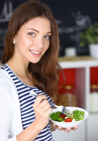 Young woman eating salad and holding a mixed salad .の写真素材