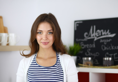 Young woman standing in kitchen at homeの写真素材