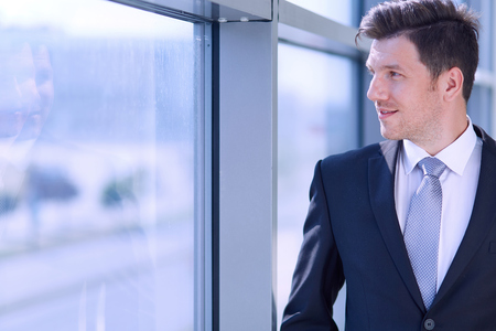 Portrait of businessman standing near window in office .の写真素材