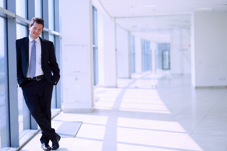 Portrait of businessman standing near window in office .の写真素材