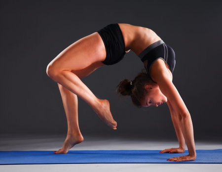 Young woman doing yoga exercise on mat .