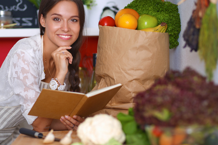 Young woman reading cookbook in the kitchen, looking for recipe .の写真素材