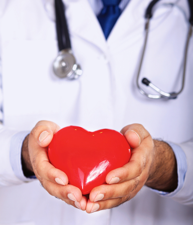Male doctor with stethoscope holding heartの写真素材