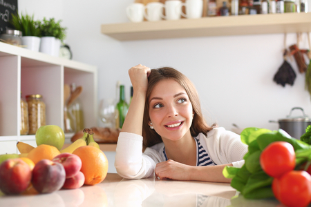 Young woman standing near desk in the kitchenの写真素材