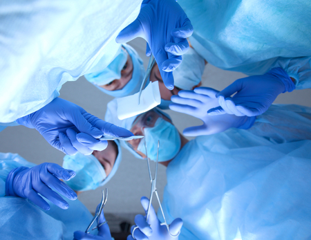 Below view of surgeons holding medical instruments in hands and looking at patientの写真素材