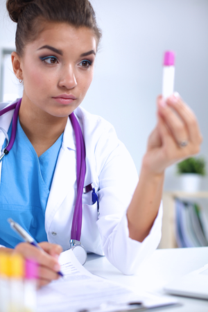 Woman researcher is surrounded by medical vials and flasks, isolated on whiteの写真素材