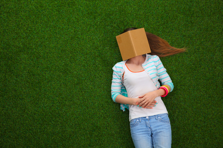 Beautiful young woman lying on green grassの写真素材