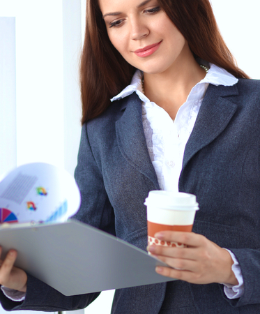 Beautiful  businesswoman enjoying coffee in bright office, sittingの写真素材