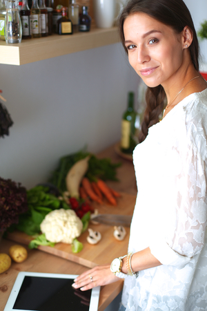Young woman using a tablet computer to cook in her kitchen .の写真素材