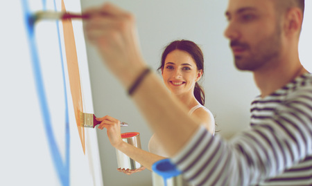 Portrait of happy smiling young couple  painting interior wall of new house.の写真素材