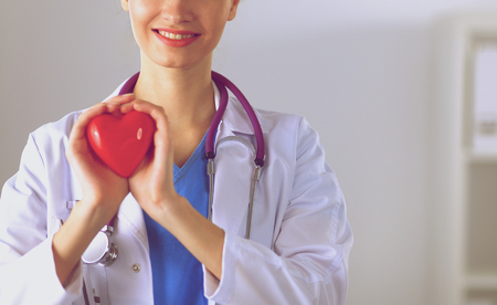 Young woman doctor holding a red heart, standing .の写真素材