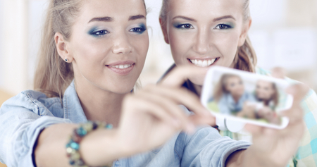 Two girls taking pictures on the phoneの写真素材