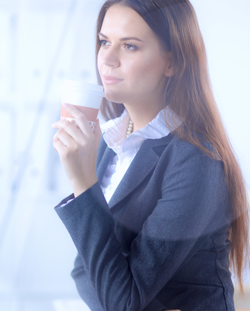 Beautiful  businesswoman enjoying coffee in bright office, sittingの写真素材
