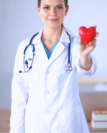 Young woman doctor holding a red heart, isolated on whiteの写真素材
