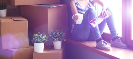 Girl sitting on windowsill at new home.の写真素材